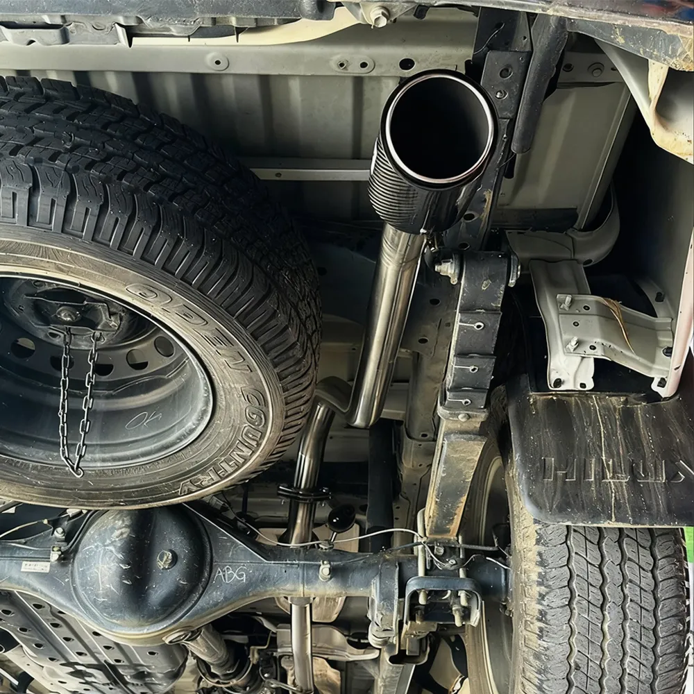 Detailed close-up of the XROAR exhaust installation on a Hilux, showing the connection points and clearances.